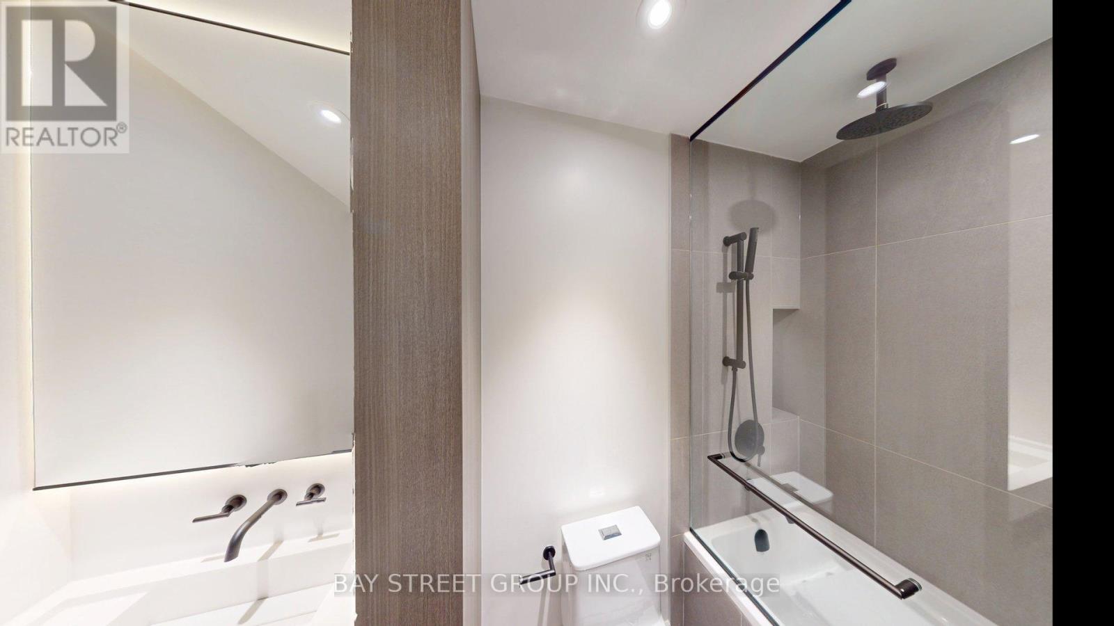 A modern bathroom with a large mirror and a white sink.