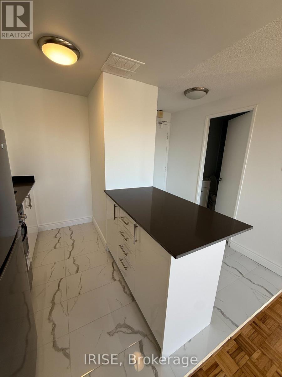 A kitchen with a refrigerator, countertop, and tiled floor.