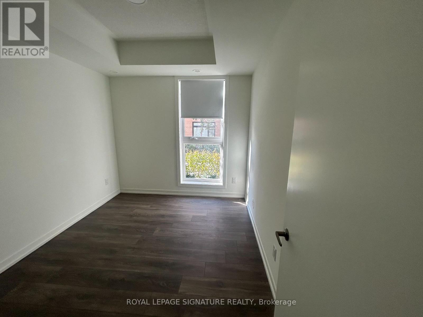 A room with a window showing a view of a building and trees outside.