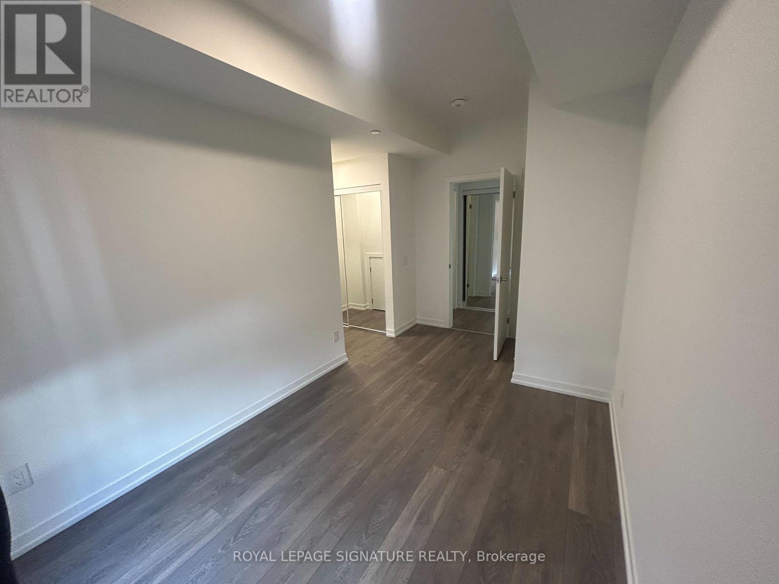 A hallway with wood flooring and white walls.