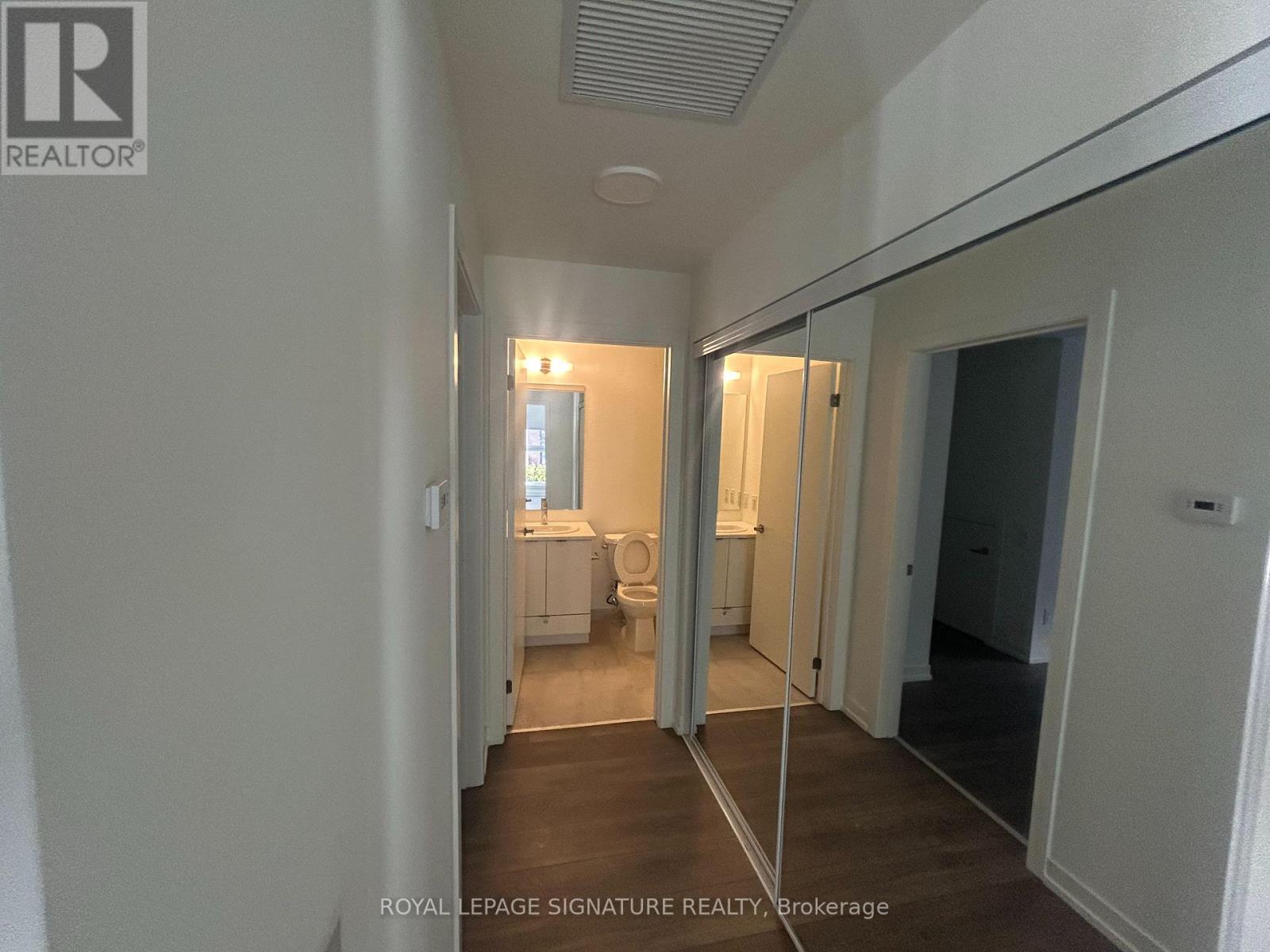 A hallway with a mirrored wall and a door on the right.