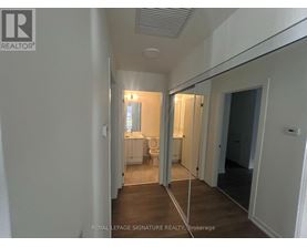 A hallway with a mirrored wall and a door on the right.