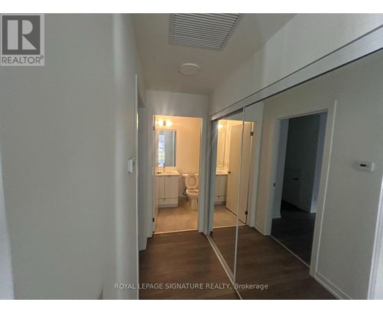 A hallway with a mirrored wall and a door on the right.