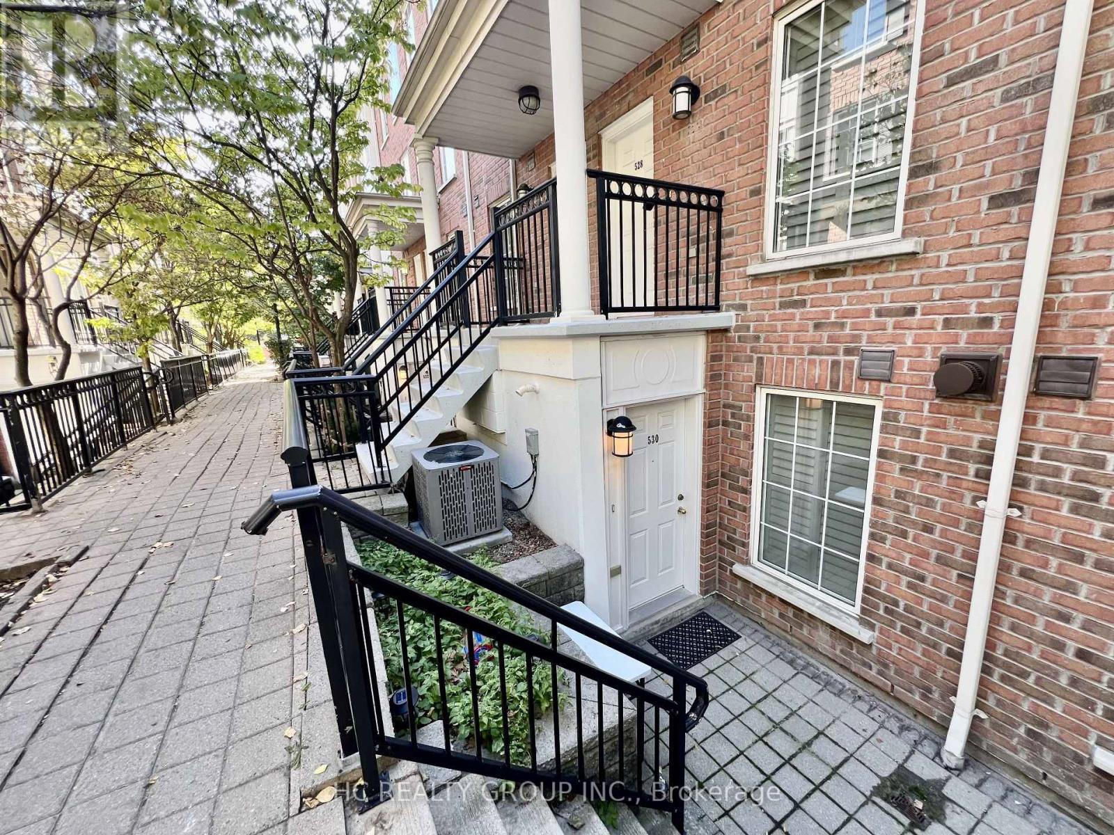 A brick building with a black railing and a white door.