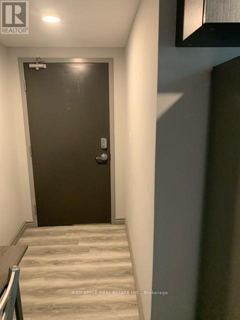 A brown door with a silver handle is in a hallway.