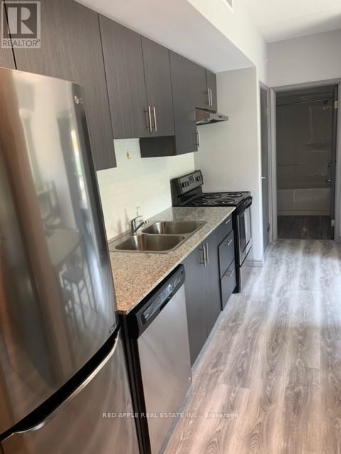 A kitchen with a stainless steel refrigerator and wooden floors.