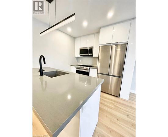A modern kitchen with a stainless steel refrigerator and a sink with a black faucet.