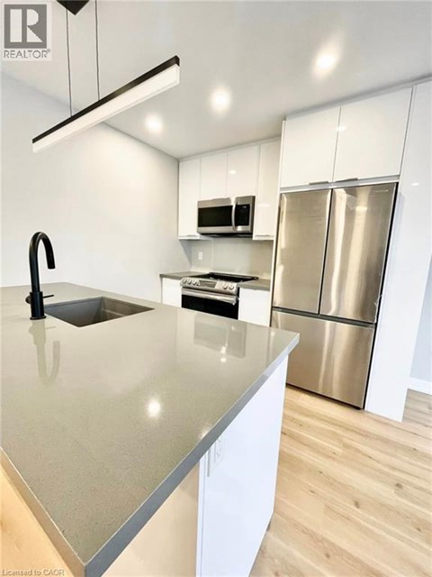 A modern kitchen with a stainless steel refrigerator and a sink with a black faucet.