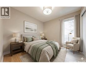 A bedroom with a bed, chair, and lamp.
