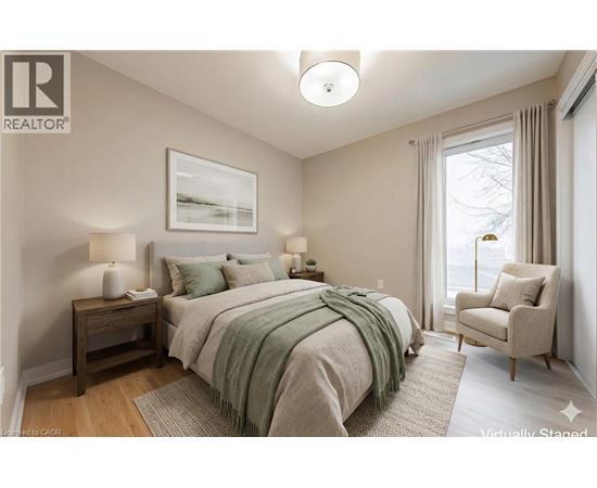 A bedroom with a bed, chair, and lamp.