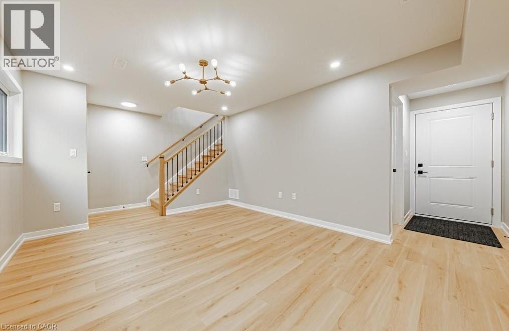 A spacious room with wooden flooring and a staircase leading to the upper level.
