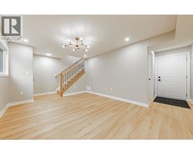 A spacious room with wooden flooring and a staircase leading to the upper level.