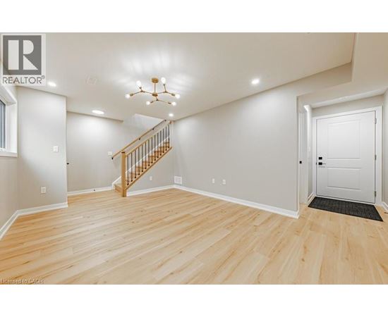 A spacious room with wooden flooring and a staircase leading to the upper level.