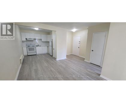 A realtor logo is on the wall of a room with a kitchenette.