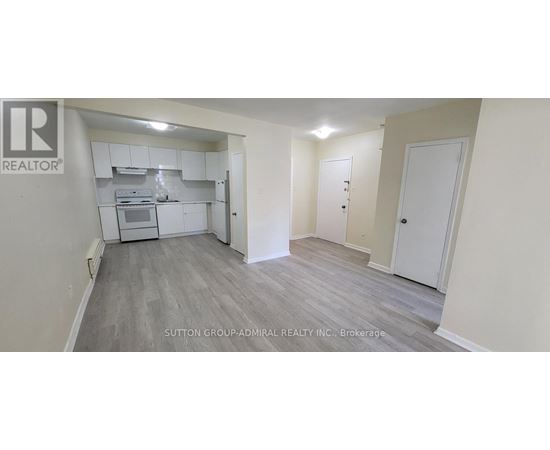 A realtor logo is on the wall of a room with a kitchenette.