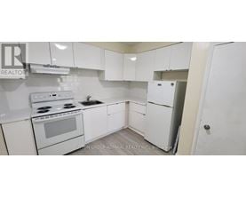 A white kitchen with a stove, sink, and refrigerator.