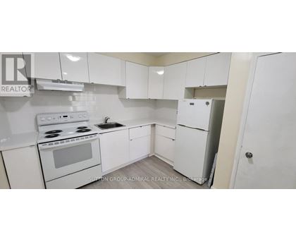 A white kitchen with a stove, sink, and refrigerator.
