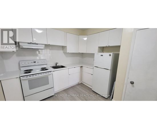 A white kitchen with a stove, sink, and refrigerator.