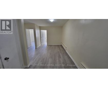 A brokerage sign is on the door of a room with wood flooring and white walls.