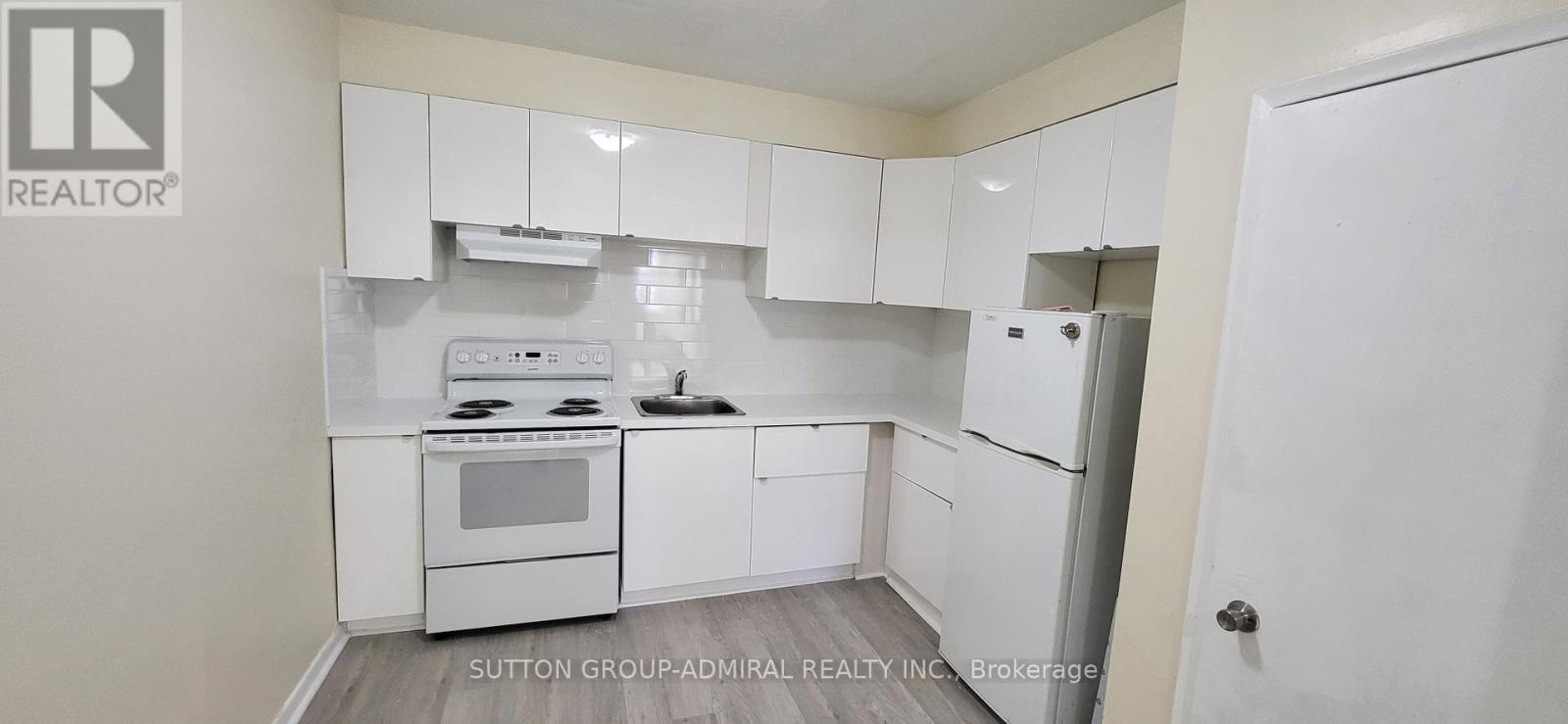 A white kitchen with a stove top oven and a refrigerator.