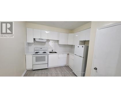 A white kitchen with a stove top oven and a refrigerator.