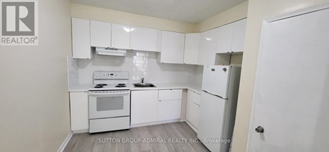 A white kitchen with a stove top oven and a refrigerator.
