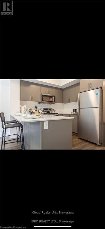 A kitchen with a refrigerator, microwave, and a bar stool.