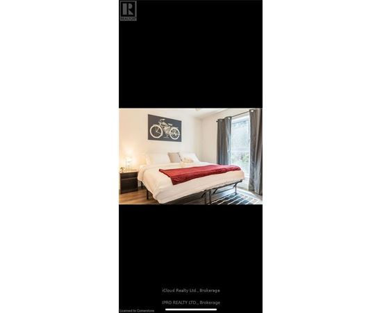 A bedroom with a white bed and a bicycle picture on the wall.