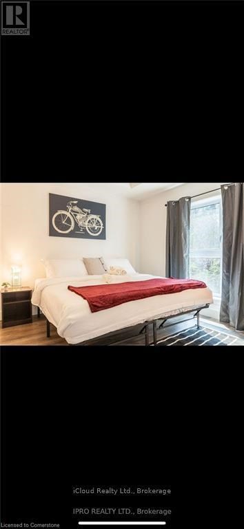 A bedroom with a white bed and a bicycle picture on the wall.