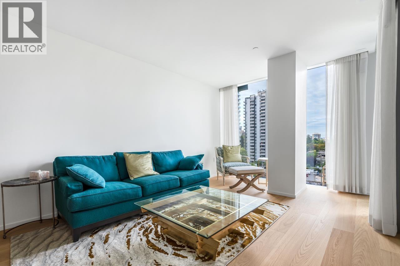 A living room with a blue couch and a glass coffee table.