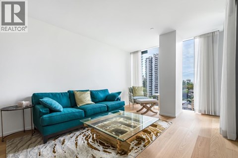 A living room with a blue couch and a glass coffee table.