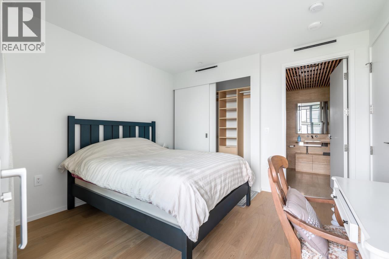 A bedroom with a bed, chair, and a wooden floor.