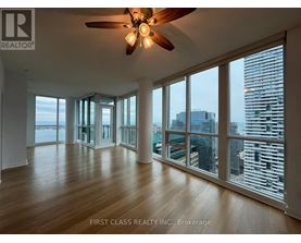 A spacious room with a ceiling fan and large windows overlooking a cityscape.