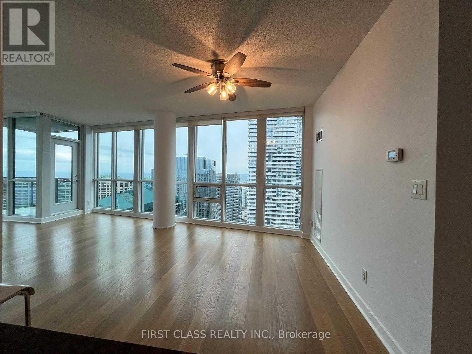 A spacious room with a ceiling fan and sliding glass doors leading to a balcony.