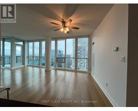 A spacious room with a ceiling fan and sliding glass doors leading to a balcony.