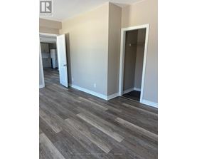 A room with wood flooring and a doorway leading to another room.