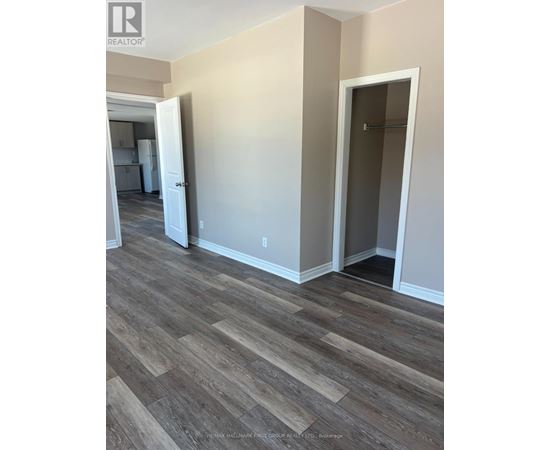 A room with wood flooring and a doorway leading to another room.