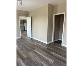 A room with a wooden floor and a doorway leading to another room.