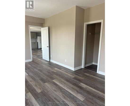 A room with a wooden floor and a doorway leading to another room.