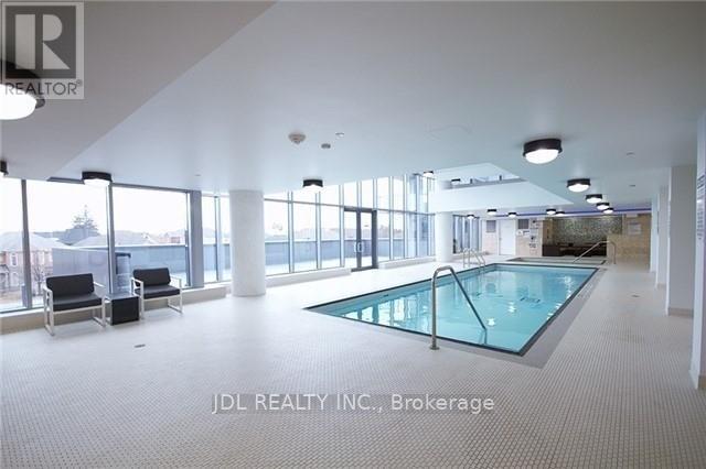 A large indoor swimming pool with a glass wall next to a seating area.