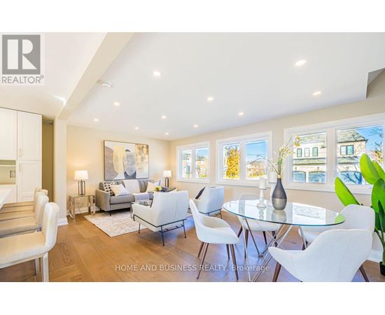 A well-lit, modern living room with a glass table and white chairs.