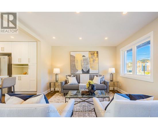 A well-lit living room with a grey sofa and a glass coffee table.