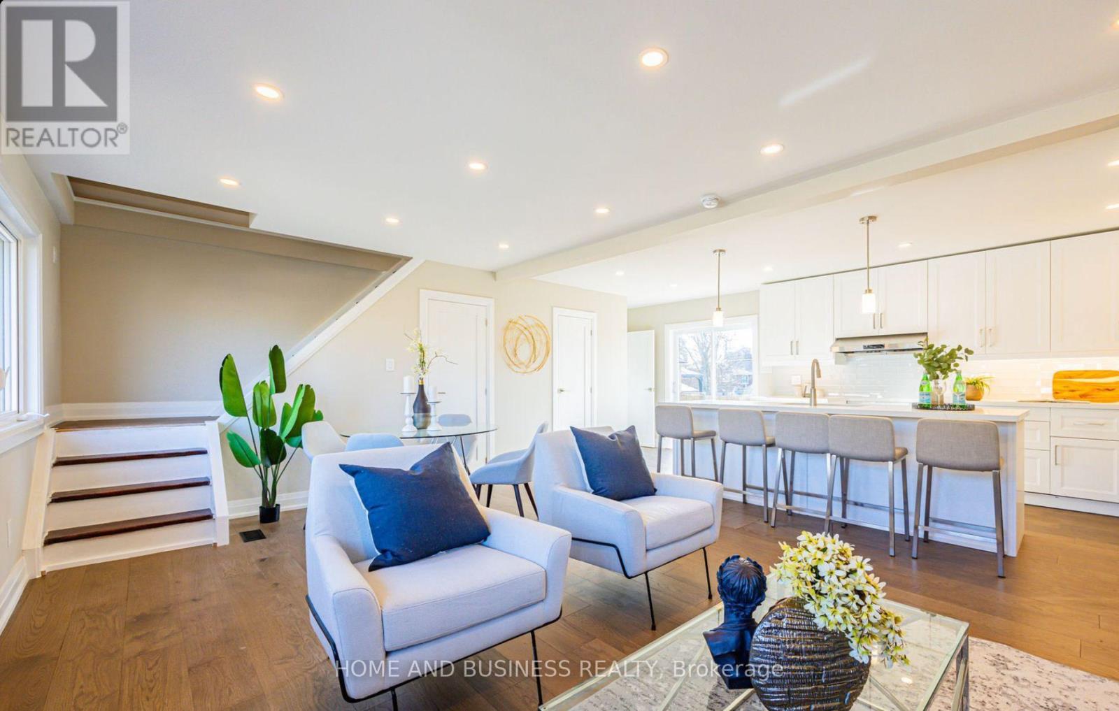 A well-lit, spacious living room with a dining area in the background.