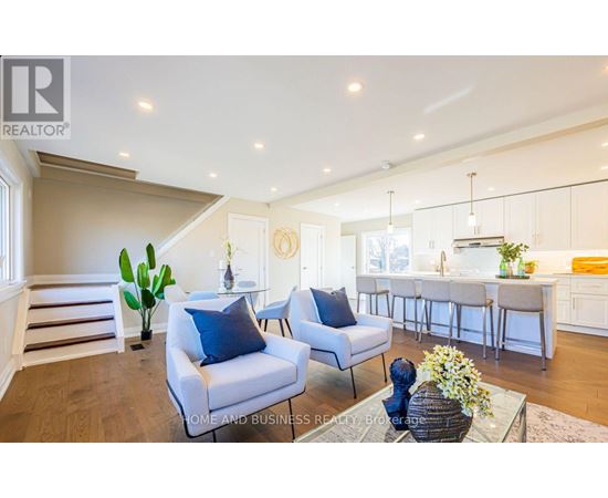 A well-lit, spacious living room with a dining area in the background.