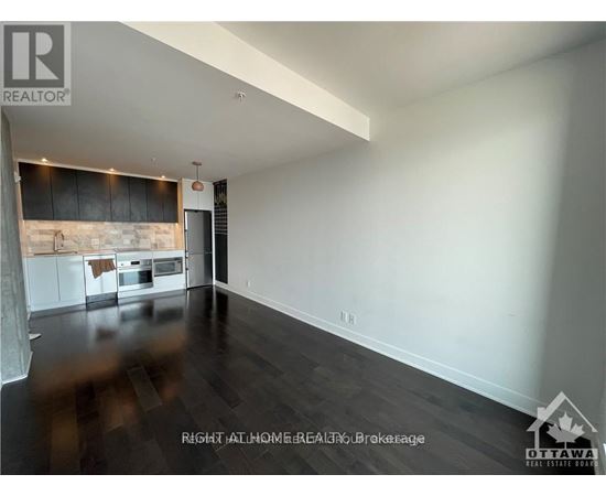 A spacious room with a kitchen area in the background.