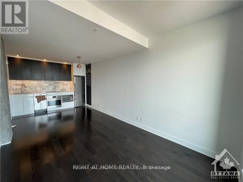 A spacious room with a kitchen area in the background.