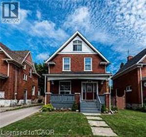 A red brick house with a porch and a front yard.