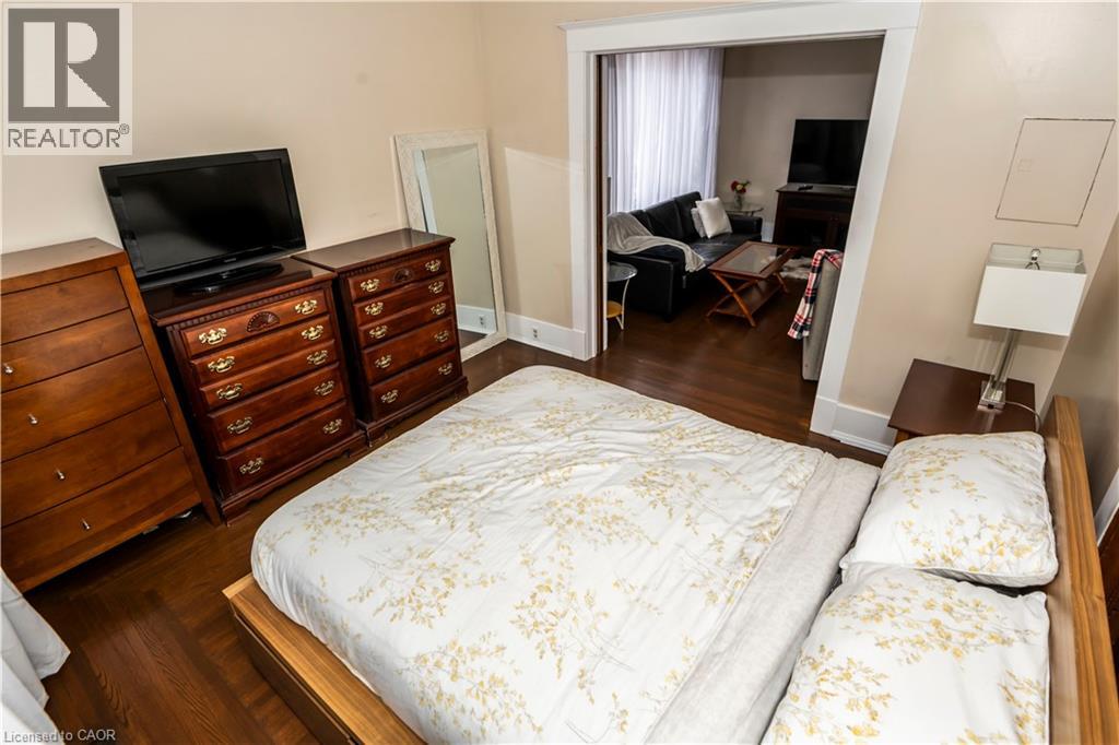 A bedroom with a large bed and a dresser with a flat screen TV on top.