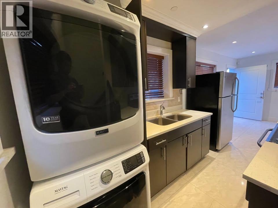 A white Maytag dishwasher is in a kitchen with black appliances.