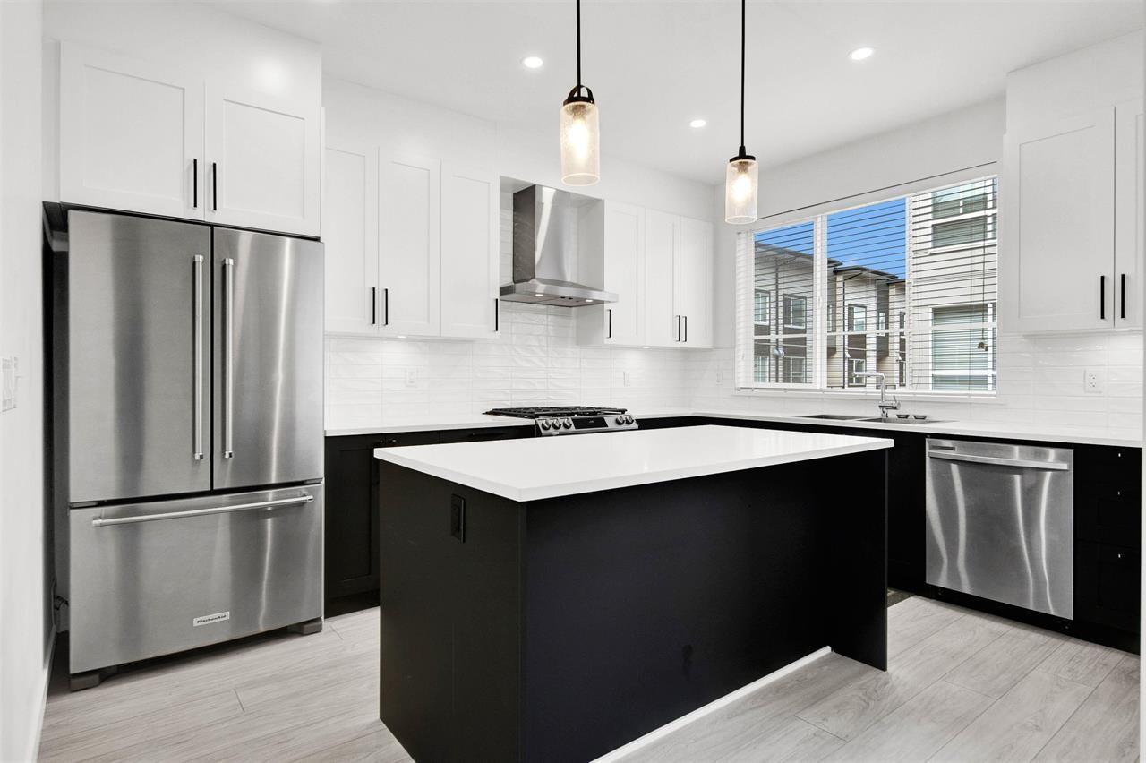 A modern kitchen with a large island and stainless steel appliances.